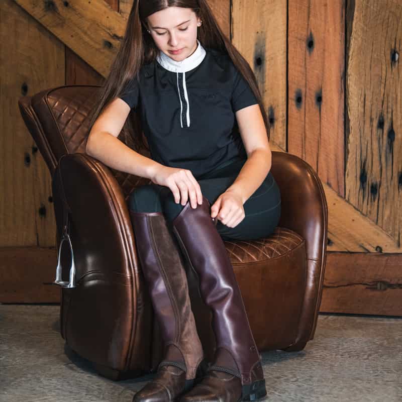 Image of a young woman wearing a pair of brown leather horse riding boots.