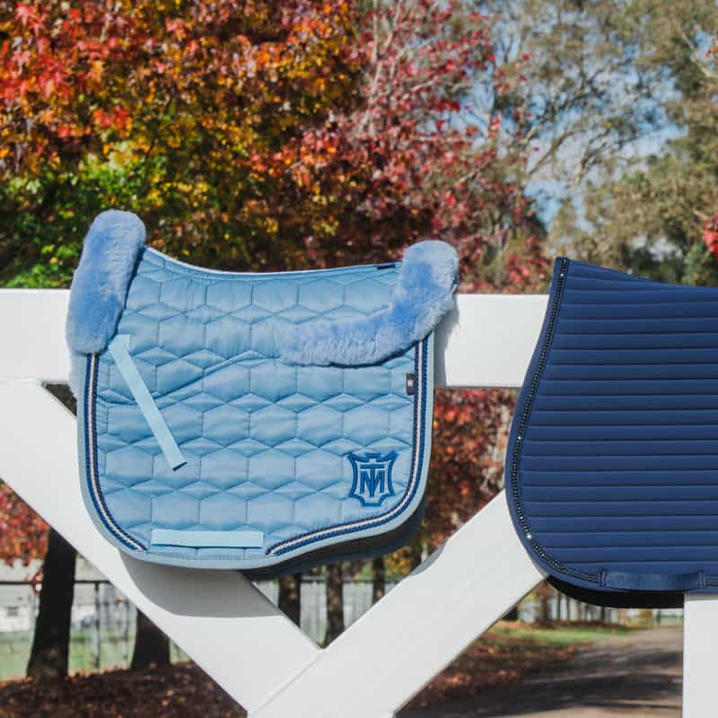 Image of a light blue and dark blue saddle pad sitting on a fence. Saddle pads available to purchase online or in-store at Saddleworld Dural, Sydney Hills DIstrict.